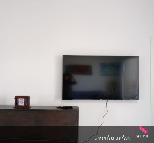 טלוויזיה תלויה על הקיר עם כבל חשמל גלוי